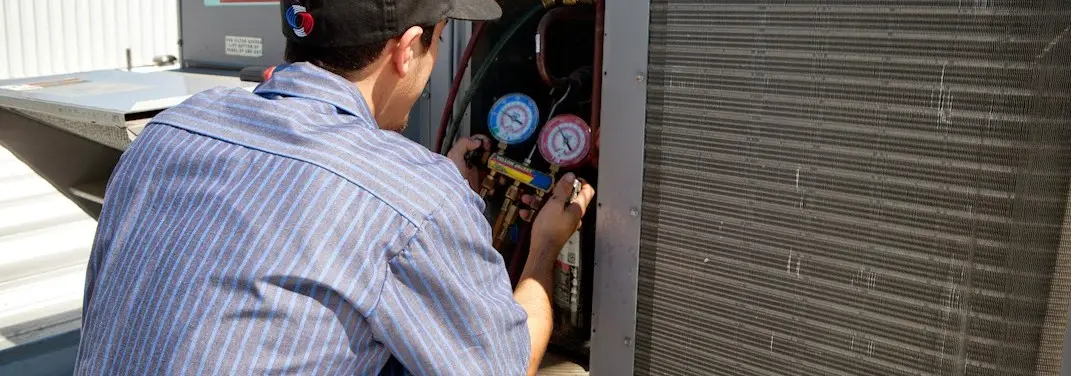 HVAC technician servicing a condenser unit in North Haledon